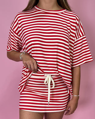 Red and white striped outfit with a drawstring detail on a pink background