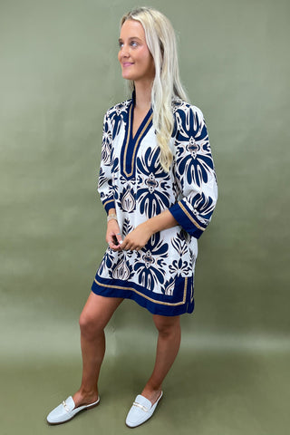 Woman wearing a white dress with blue floral patterns on a green background