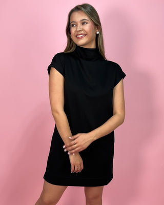 Woman wearing a black dress against a pink background