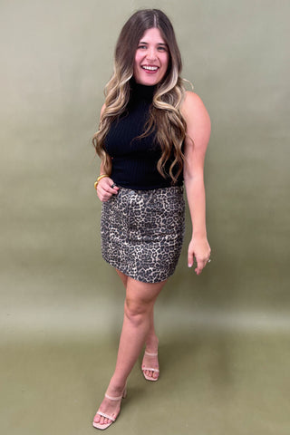 Woman wearing a black top and patterned skirt against a green background