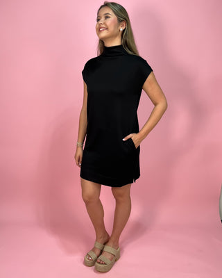 Woman wearing a black dress against a pink background