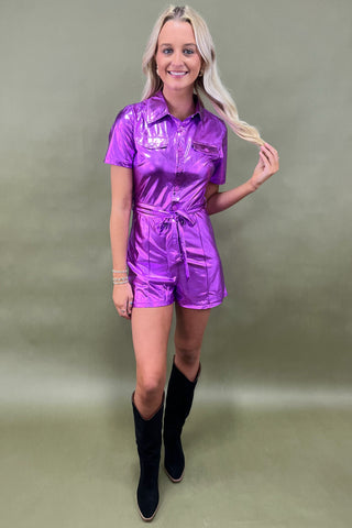Woman wearing a shiny purple jumpsuit against a plain background