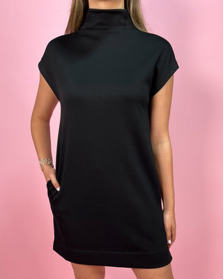 Black dress worn by a person on a pink background