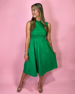 Woman wearing a green dress against a pink background
