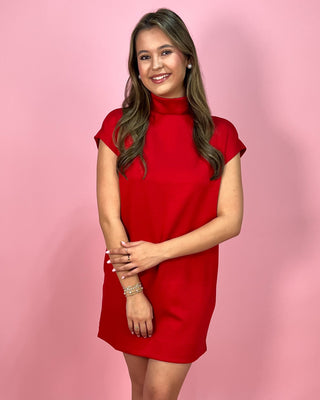Woman wearing a red dress against a pink background