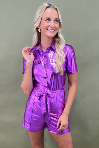 Woman wearing a shiny purple romper against a green background