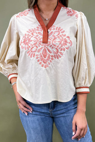 White blouse with red embroidery and blue jeans on a green background