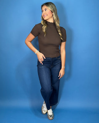 Chocolate brown ribbed mock neck top with short sleeves, a fitted silhouette, and delicate scalloped trim.