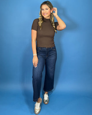 Chocolate brown ribbed mock neck top with short sleeves, a fitted silhouette, and delicate scalloped trim.