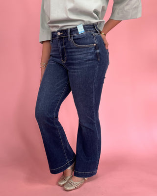 Person wearing blue jeans with a pink background