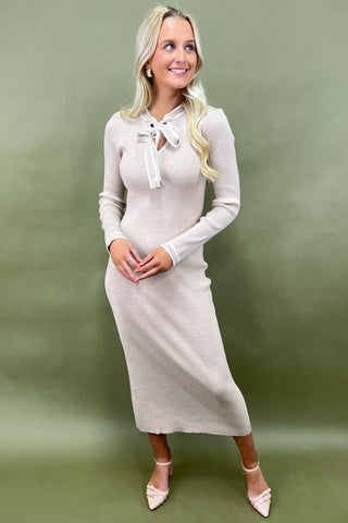 Woman wearing a beige dress with a white collar against a green background