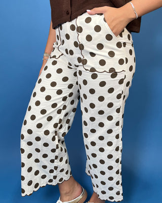 Ivory wide leg pants with brown polka dots, scalloped trim, front pockets, and a cropped fit.