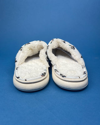 Cozy white duck slippers with cushioned interior displayed against a solid blue background. 