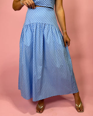 Person wearing a blue polka dot dress on a pink background