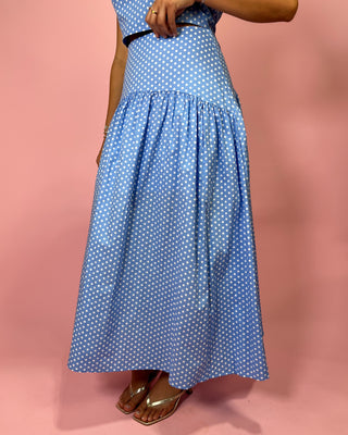 Person wearing a blue polka dot dress on a pink background