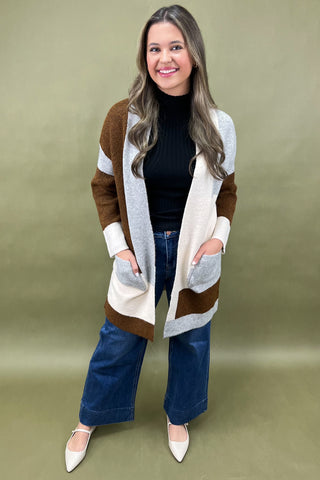 Woman wearing a long, patterned cardigan against a solid background