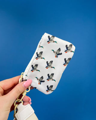 White duck print dual pouch wristlet with detachable strap, two zippered compartments, and gold-tone hardware.