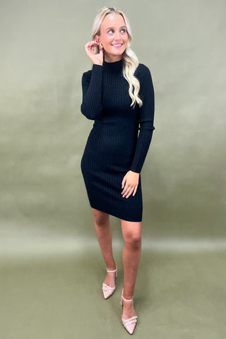 Woman wearing a black ribbed dress against a green background
