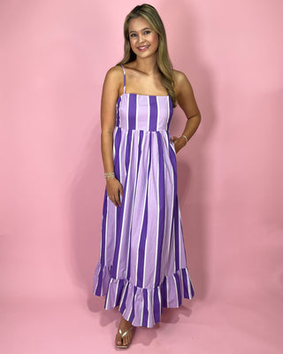 Woman wearing a purple and white striped dress against a pink background
