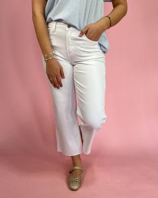 Person wearing white pants and a light blue top on a pink background