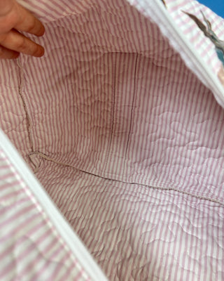Ida Mae Home quilted duck print duffle bag with striped fabric, padded handles, spacious zip-top compartment, available in pink or blue.