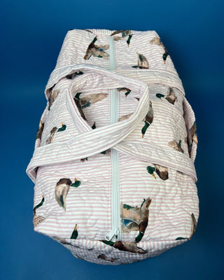 Ida Mae Home quilted duck print duffle bag with striped fabric, padded handles, spacious zip-top compartment, available in pink or blue.