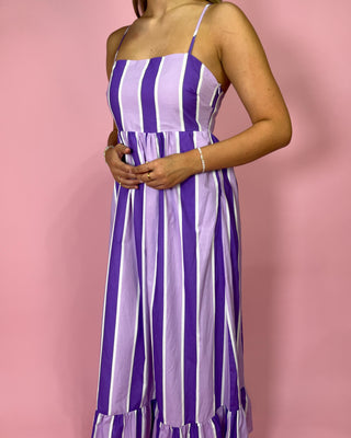 Purple and white striped dress worn by a person on a pink background