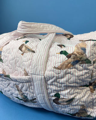 Ida Mae Home quilted duck print duffle bag with striped fabric, padded handles, spacious zip-top compartment, available in pink or blue.