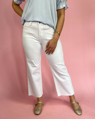Person wearing a light blue top and white pants on a pink background