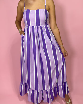 Purple and white striped dress worn by a person on a pink background