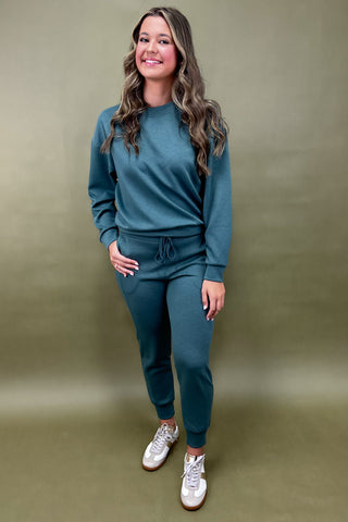 Woman wearing a teal tracksuit against a green background