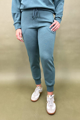 Person wearing a blue tracksuit with white sneakers on a beige background