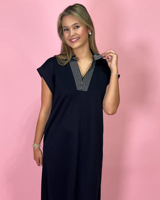 Woman wearing a black dress with a striped collar against a pink background