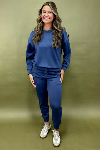 Woman wearing a blue tracksuit against a green background