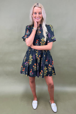 Woman wearing a dark floral dress against a plain background