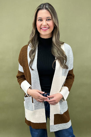 Woman wearing a brown and beige striped cardigan against a green background