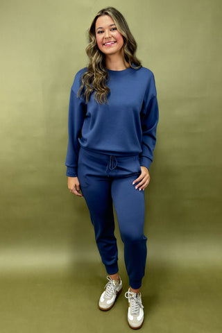 Woman wearing a blue outfit with white sneakers against a green background