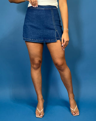 Dark wash denim skort with a flattering fitted silhouette, contrast stitching, and a chic front slit detail.