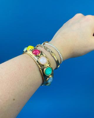 Gold-tone hinged bracelet with large faceted colored stones available in olive green, multicolor, and smoky brown.