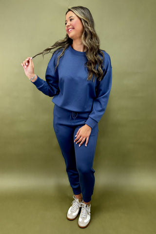 Woman wearing a blue tracksuit against a green background