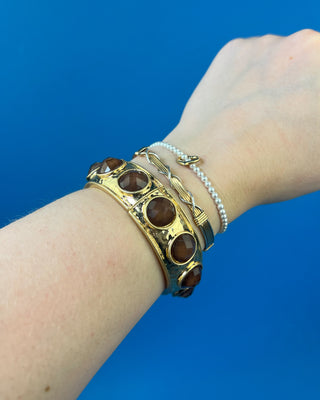 Gold-tone hinged bracelet with large faceted colored stones available in olive green, multicolor, and smoky brown.