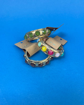 Gold-tone hinged bracelet with large faceted colored stones available in olive green, multicolor, and smoky brown.