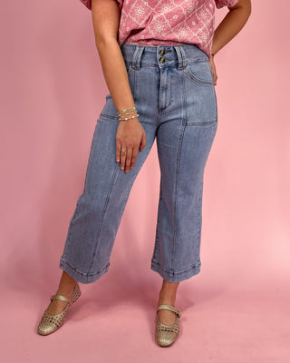 Person wearing blue jeans and a pink top on a pink background