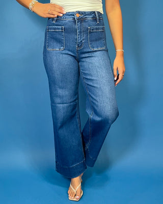 Medium wash high-rise wide leg jeans with front patch pockets, subtle fading, and statement cuffed hems.