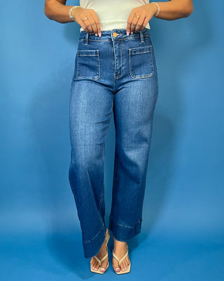 Medium wash high-rise wide leg jeans with front patch pockets, subtle fading, and statement cuffed hems.