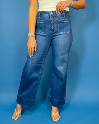 Medium wash high-rise wide leg jeans with front patch pockets, subtle fading, and statement cuffed hems.