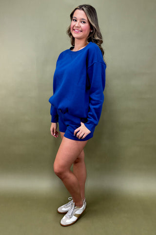 Woman wearing a blue sweater and white sneakers against a green background
