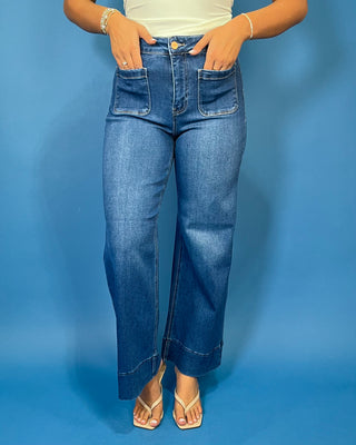 Medium wash high-rise wide leg jeans with front patch pockets, subtle fading, and statement cuffed hems.