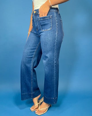 Medium wash high-rise wide leg jeans with front patch pockets, subtle fading, and statement cuffed hems.