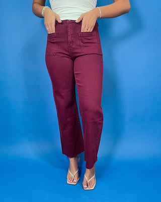 Burgundy high-rise cropped straight leg jeans with front patch pockets and a trendy raw hem.
